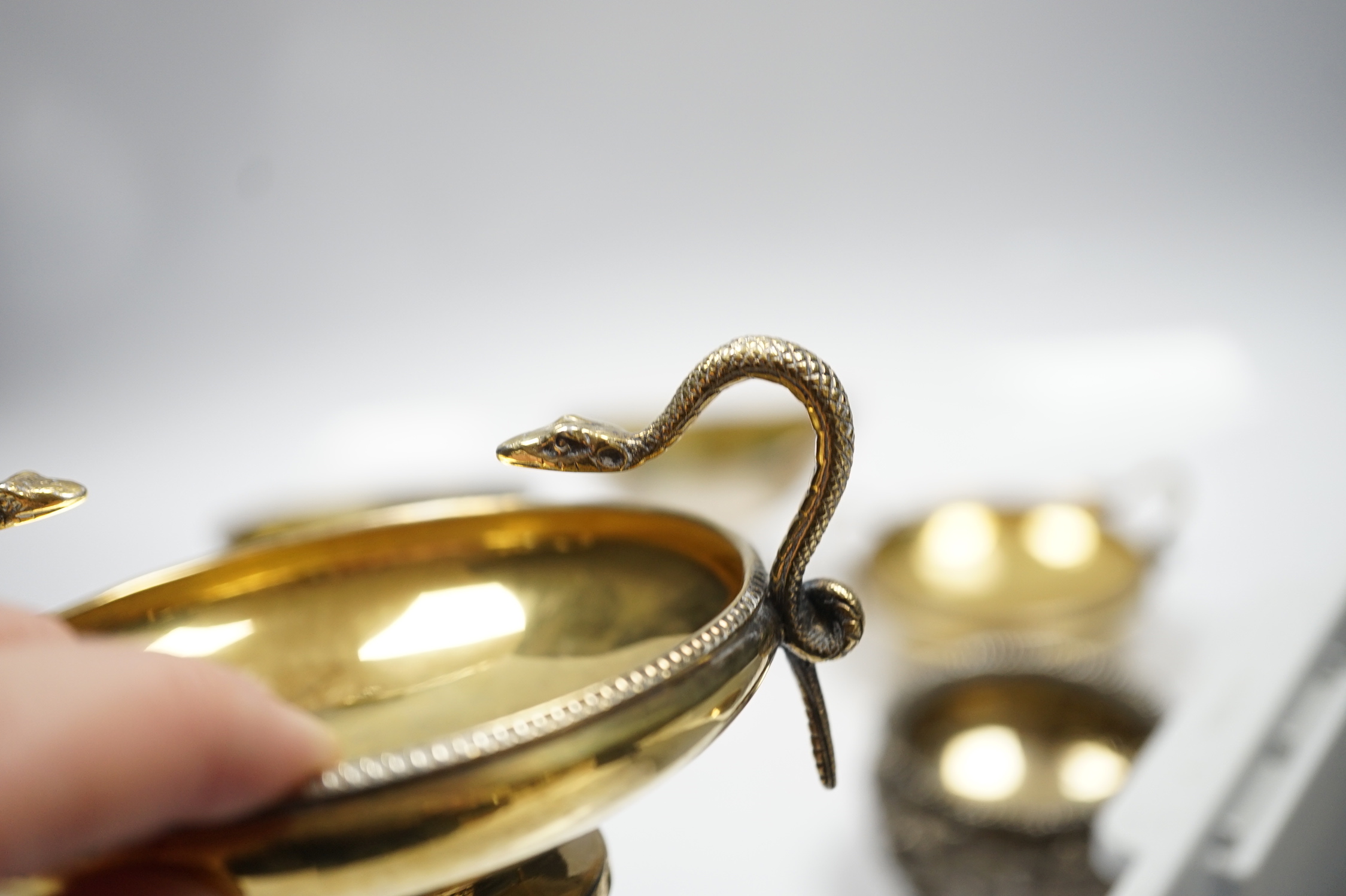 A pair of George V silver gilt shallow pedestal salts, with twin serpent handles, William Hutton & Sons, Ltd, Sheffield, 1928, width 11.8cm over handles, together with two matched pairs of Georgian silver salts, 20.3oz.